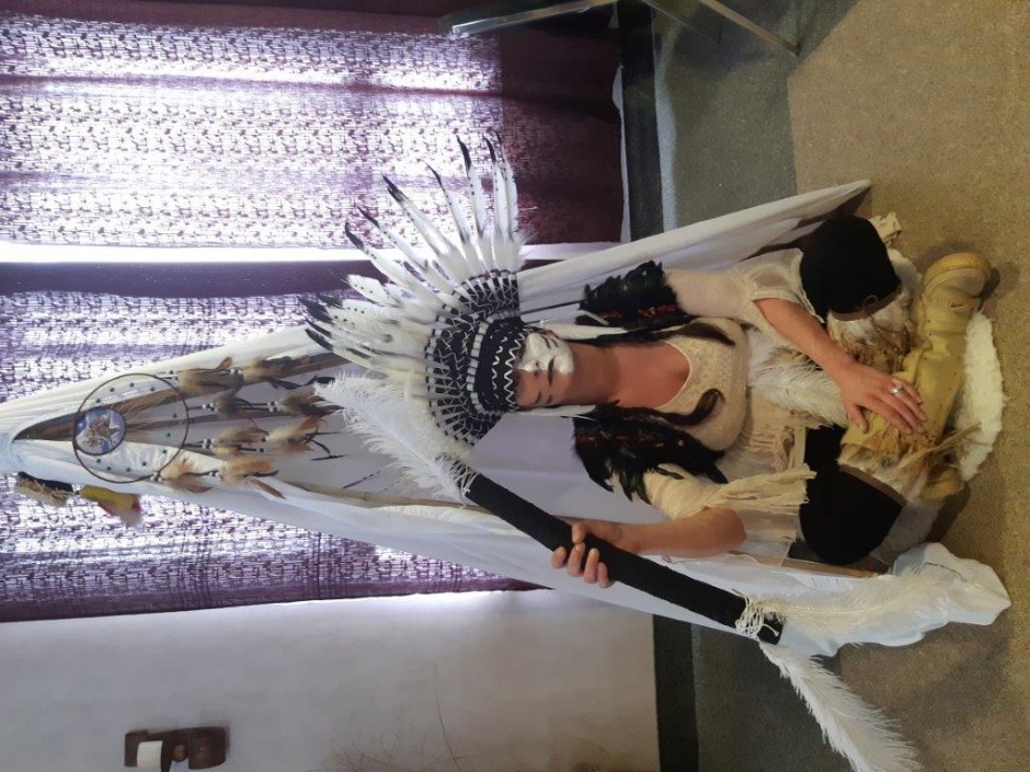 Woman in indigenous clothing and head dress sitting on the floor